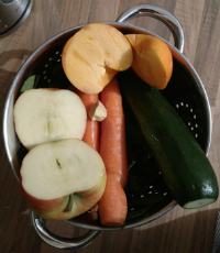 Warzywa i owoce przed wyciśnięciem. W kolejności przypadkowej: jabłko, kaka, marchew, cukinia, imbir, szpinak i jarmuż.